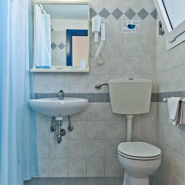 Simple bathroom with shower, sink, toilet, and hairdryer.